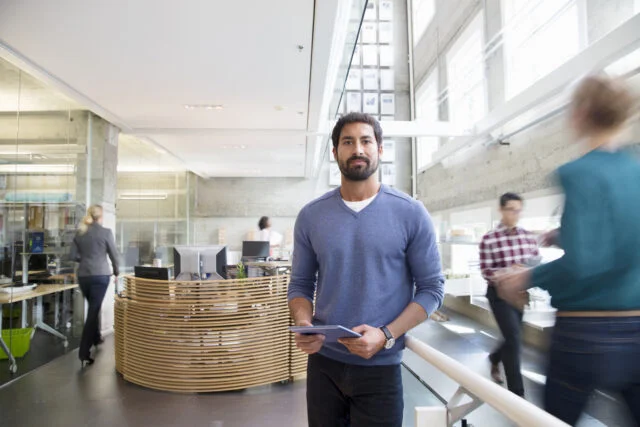 Man holding tablet in modern office, showing why a well-being strategy needs to support the whole workforce