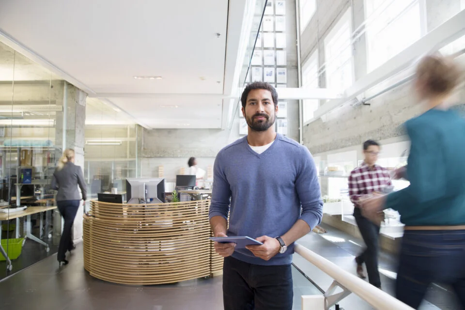 Man holding tablet in modern office, showing why a well-being strategy needs to support the whole workforce