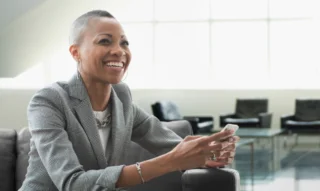 Smiling woman using smartphone indoors.