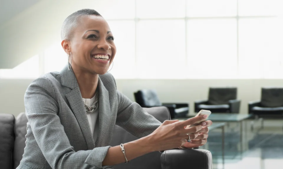 Smiling woman using smartphone indoors.