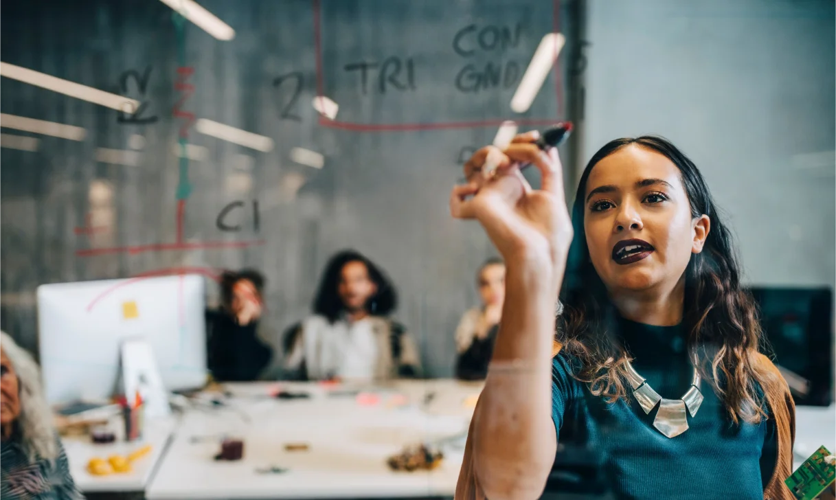 Woman writing on glass wall in meeting