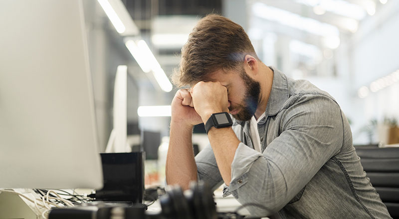 Exhausted office worker sitting at desk, struggling with burnout and grind culture