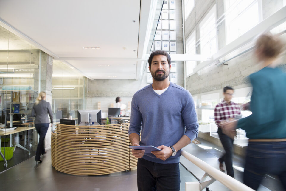 Man holding tablet in modern office, showing why a well-being strategy needs to support the whole workforce